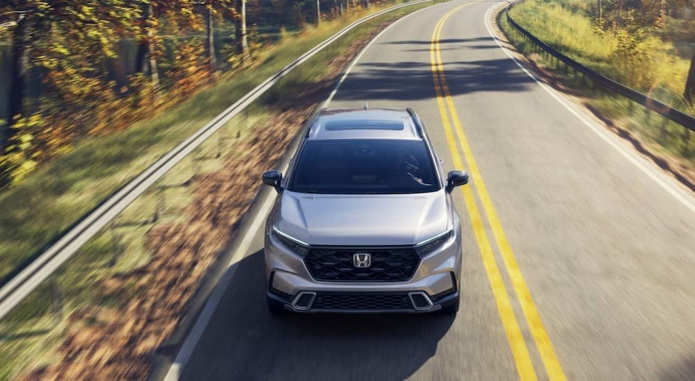 A silver 2026 Honda CR-V Hybrid driving on a highway.