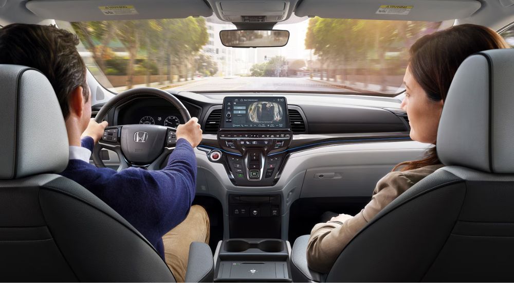 Front interior view of a couple driving a 2027 Honda Odyssey Elite.