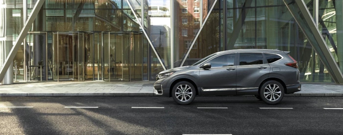 A gray 2022 Honda CR-V Hybrid Touring parked by a glass building.