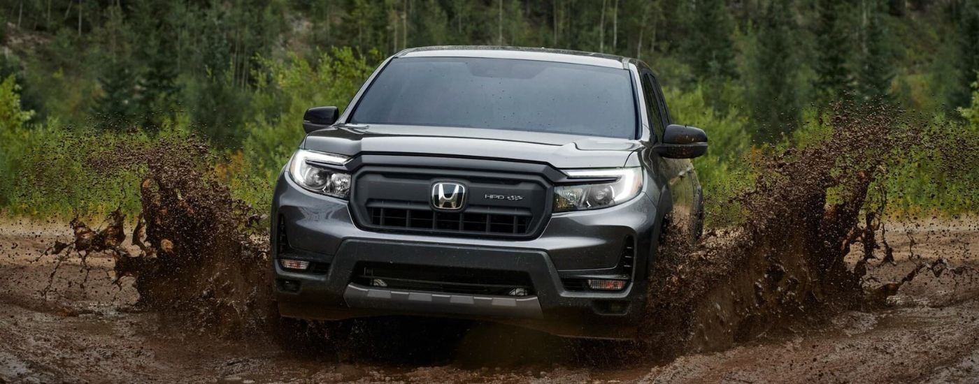 A gray 2024 Honda Ridegeline HPD shown driving through mud.