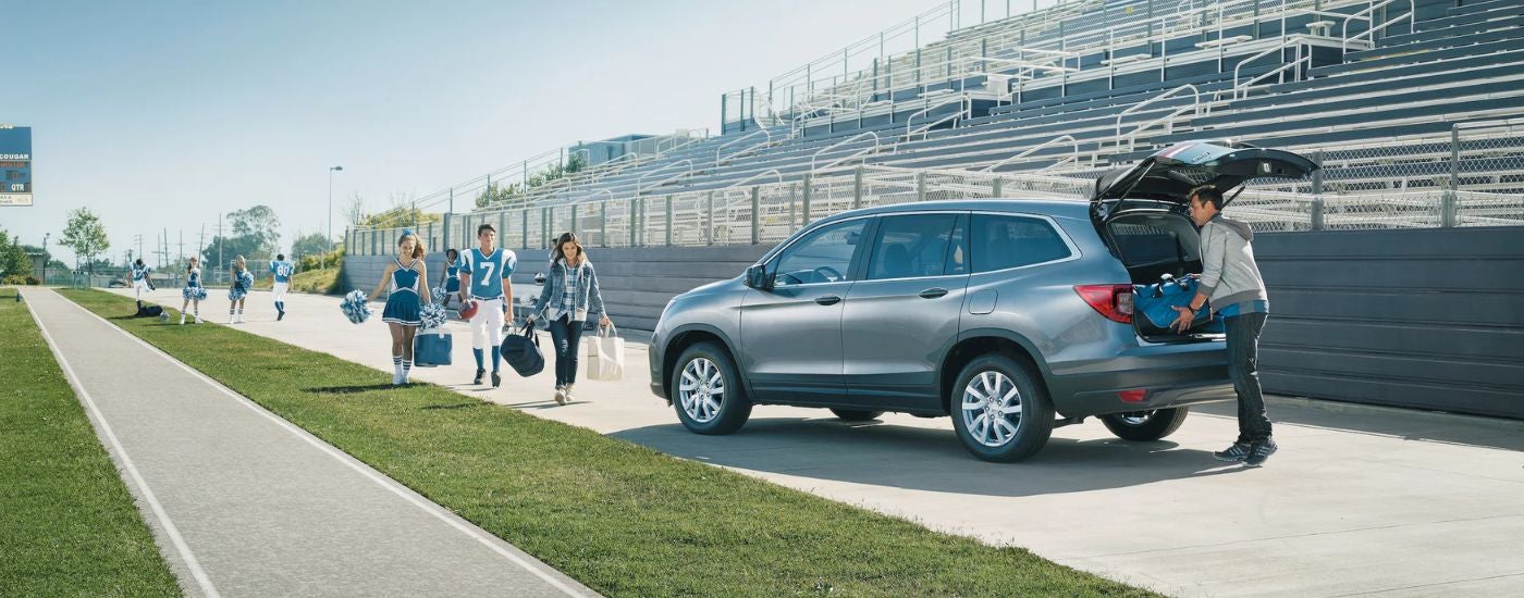 A silver 2021 Honda Pilot parked at a football game with rear gate open.