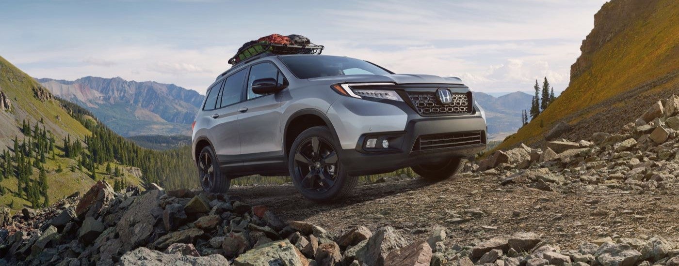 White 2020 Honda Passport driving off-road on a hill.