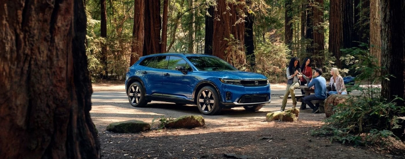 Blue 2021 Honda Prologue Elite parked off-road in a forest.