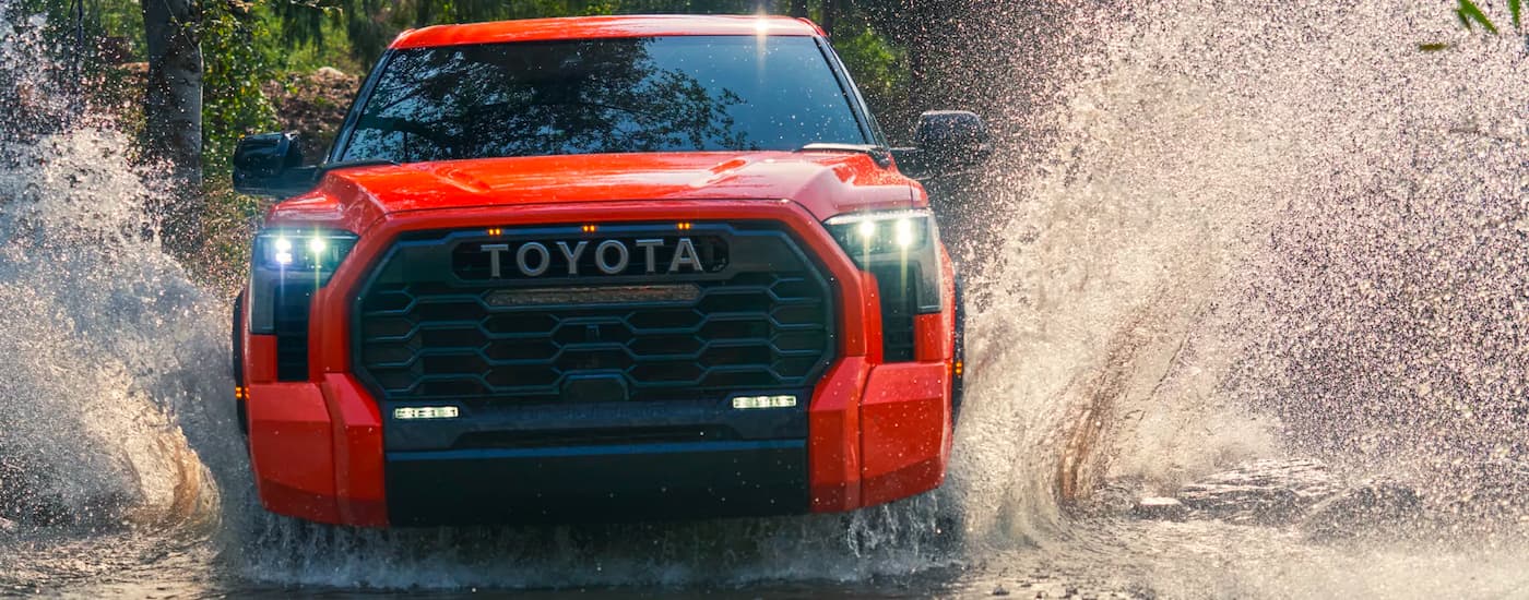 Orange 2022 Toyota Tundra TRD Pro driving through a creek