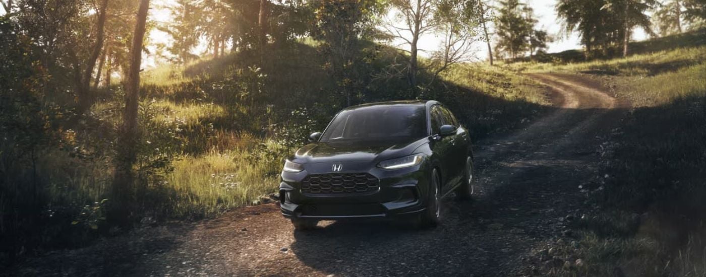Black 2023 Honda HR-V driving along a dirt road