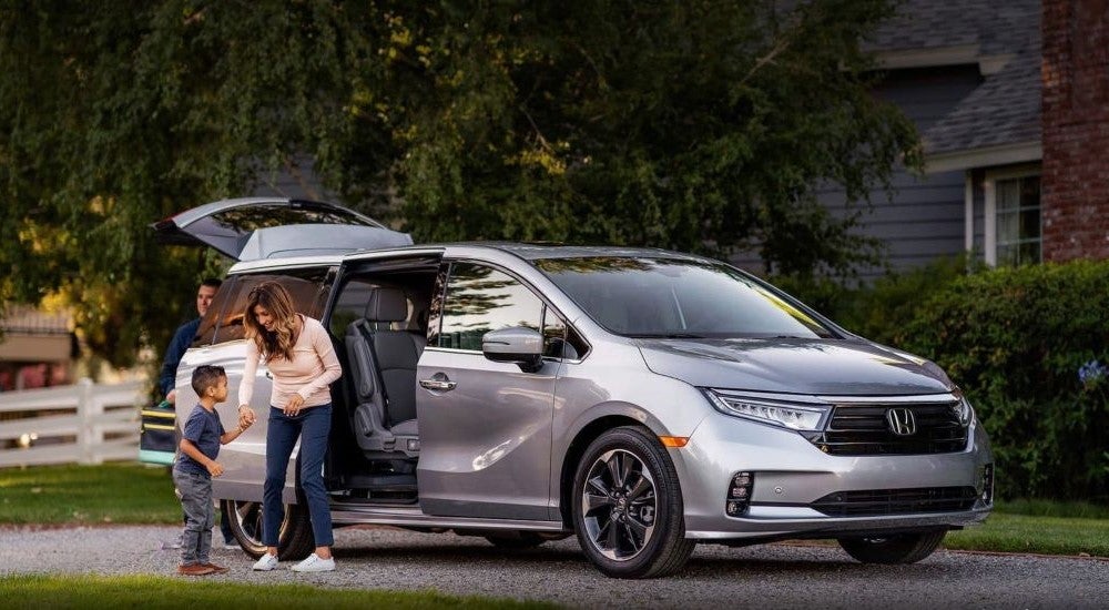People leaving a silver 2026 Honda Odyssey with an open door.