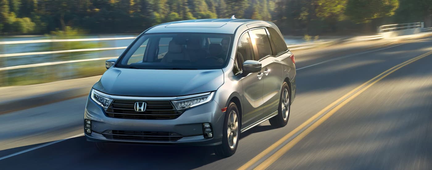 Silver 2024 Honda Odyssey driving down an open road.