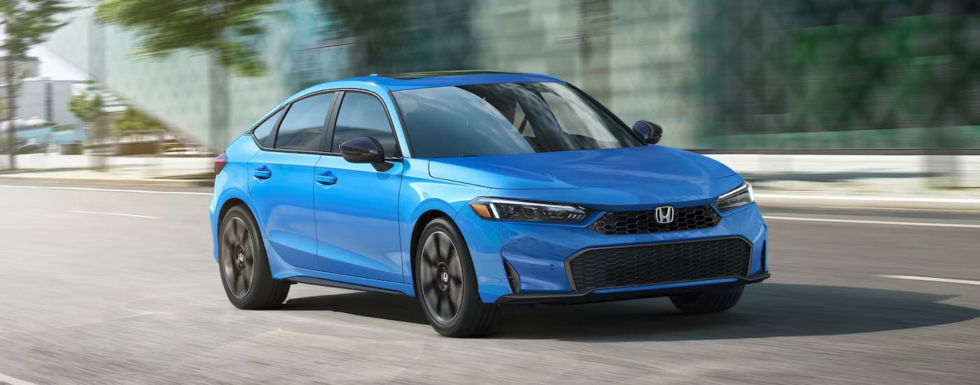 Blue 2026 Honda Civic driving down an open road.