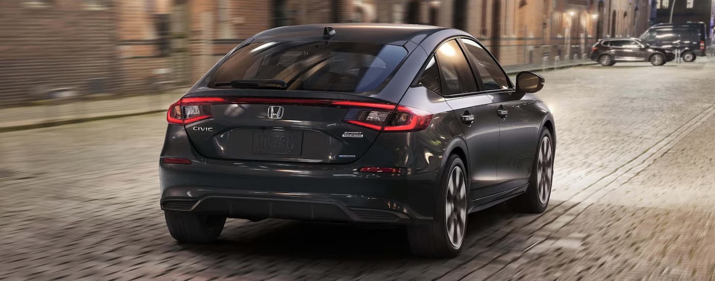 Rear of a black 2026 Honda Civic driving down a city street.