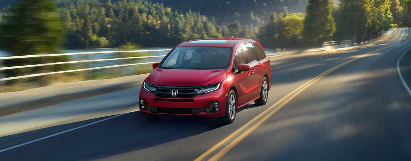 Red 2026 Honda Odyssey driving down an open road.