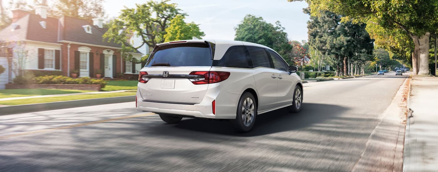 Rear of a white 2026 Honda Odyssey driving down a road.