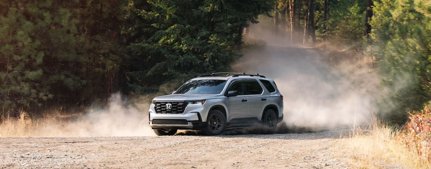 White 2025 Honda Pilot TrailSport driving off-road.