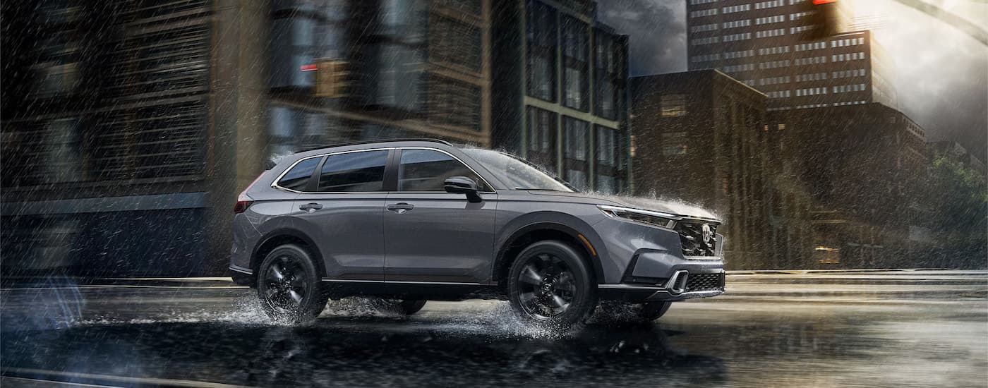 Grey 2026 Honda CR-V driving down a rainy street.