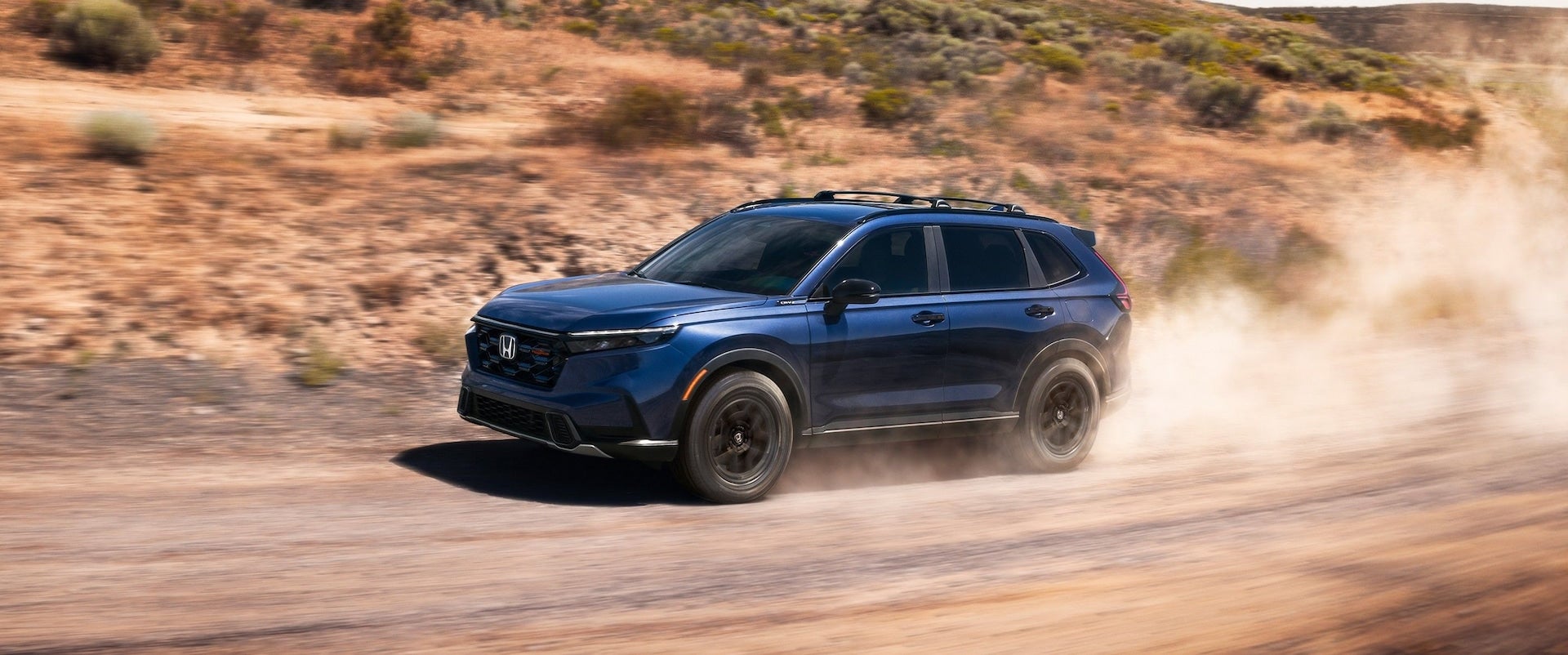Blue 2026 Honda CR-V TrailSport Hybrid driving off-road.