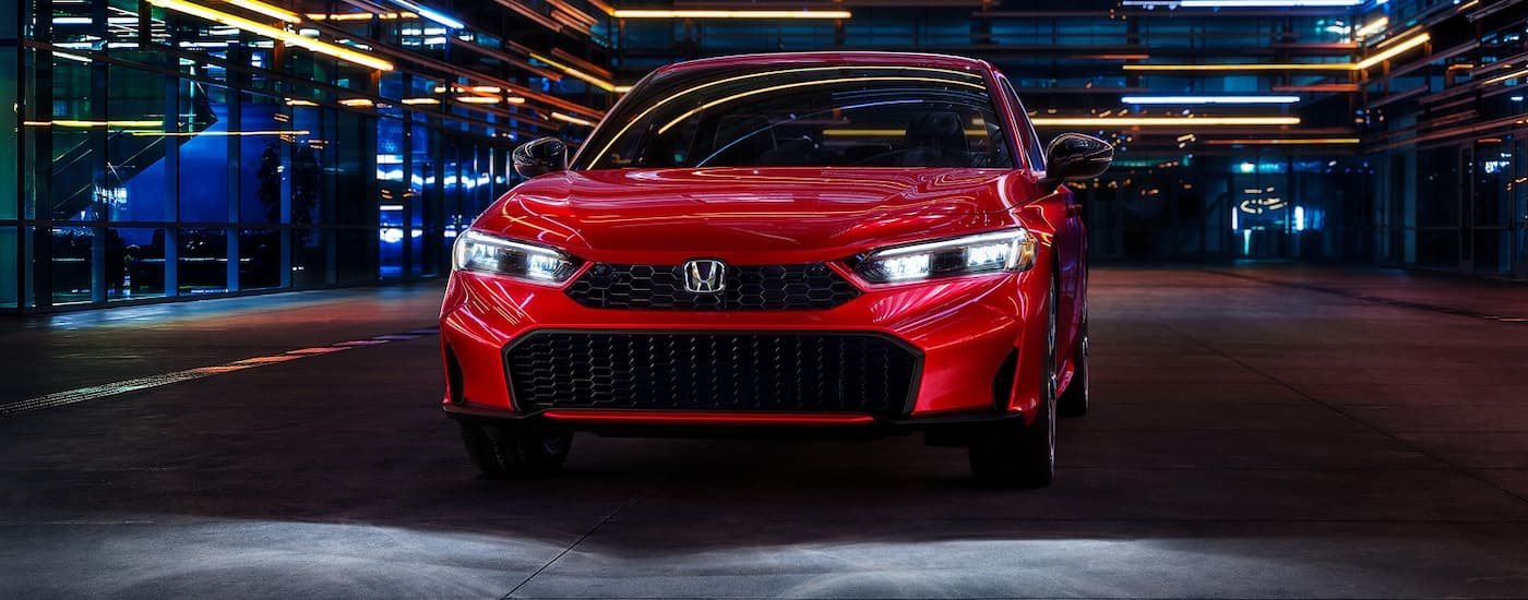 Red 2026 Honda Civic driving down a city street.