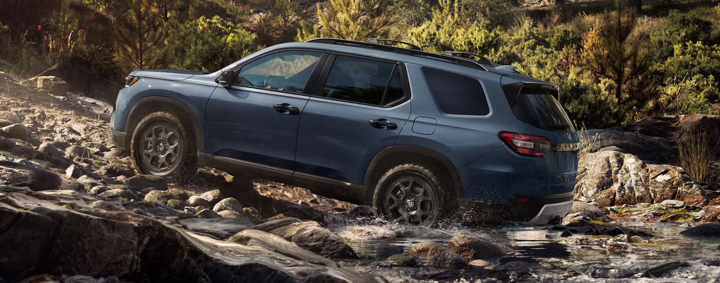 Rear of a grey 2026 Honda Pilot driving up a hill.