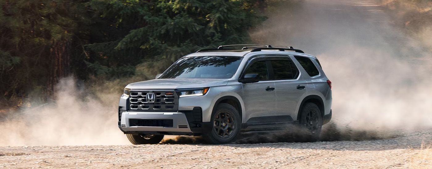 2026 Honda Pilot driving on a dirt road.