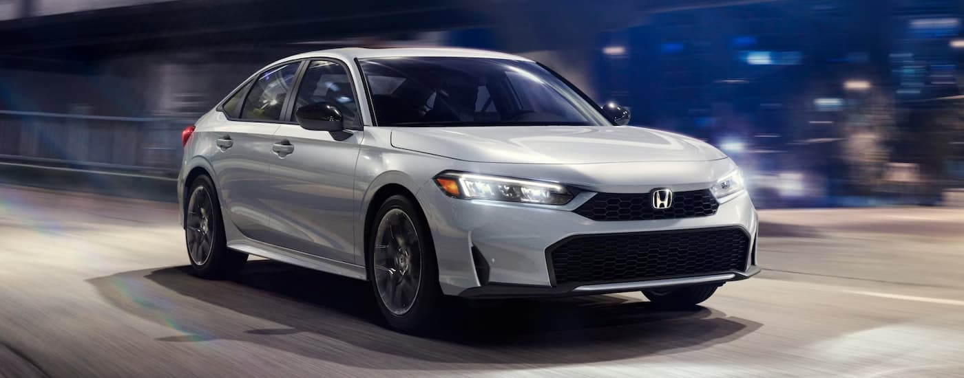 Silver 2025 Honda Civic driving at night to a Honda dealer near Anniston